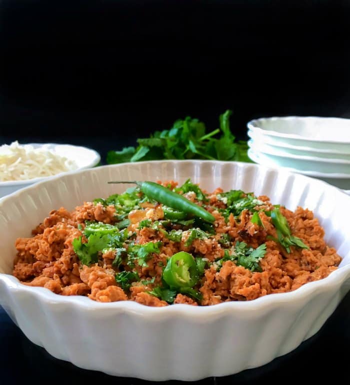 Hyderabadi Dum ka Keema in a bowl with plates around it