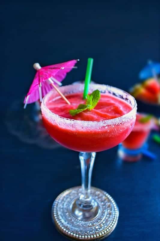 watermelon vodka slushie in a tall glass with umbrella 