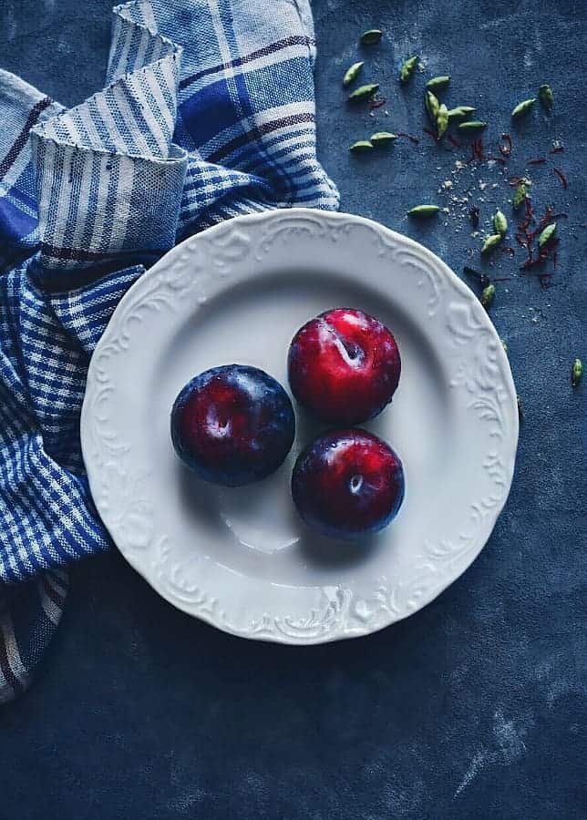 plums in a white plate with check napkin