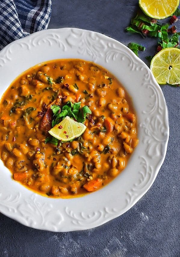 coconut black eyed peas in a white boal with sliced lemons and chopped cilantro