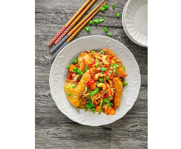 quick stir fry potstickers in a white plate on wooden table.