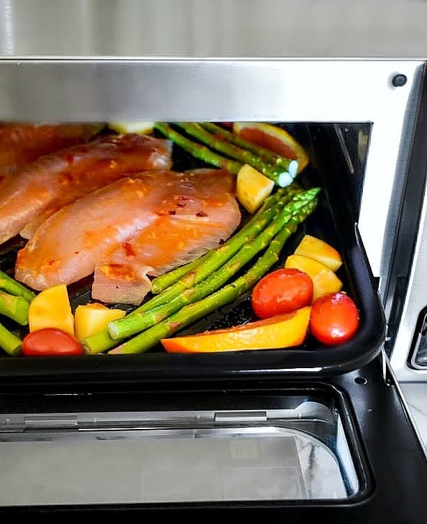 Sheet pan with vegetable and fish in the oven.