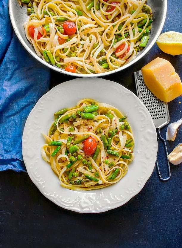 Lemon Asparagus Pasta with Peas and Tomatoes recipe on a white plate and black table