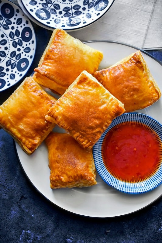 Indian Chicken Puffs on a white plate with sauce.