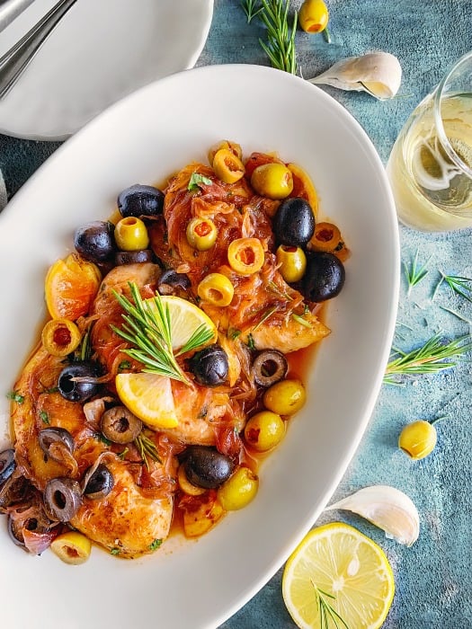 Mediterranean Chicken Recipe on a white plate with olives, onion and lemons